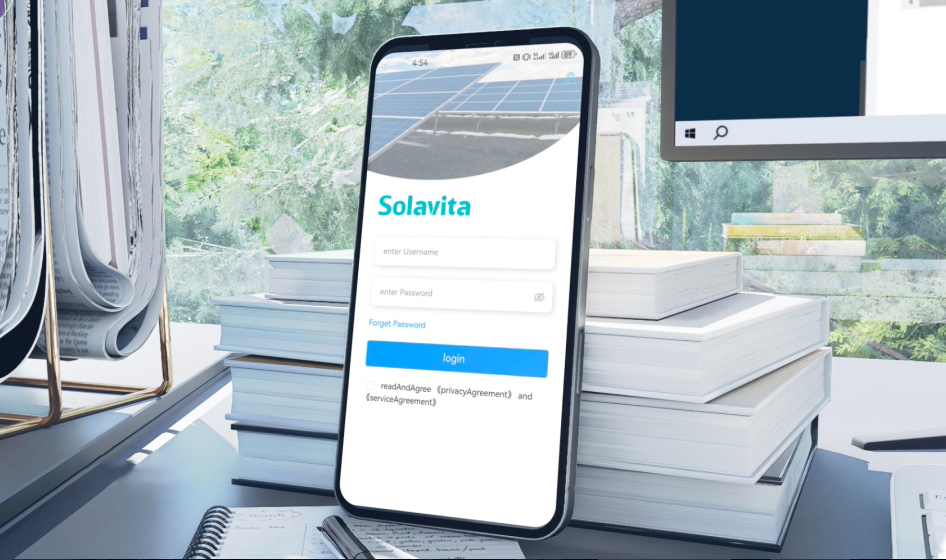 The Solavita Cloud energy management platform displayed on a large screen, showing a detailed plant list interface with various solar power station data including location, capacity, and system status indicators. A smartphone with the Solavita Cloud login screen is visible in the foreground, showcasing the platform’s accessibility across devices. Set in a modern workspace with greenery visible outside